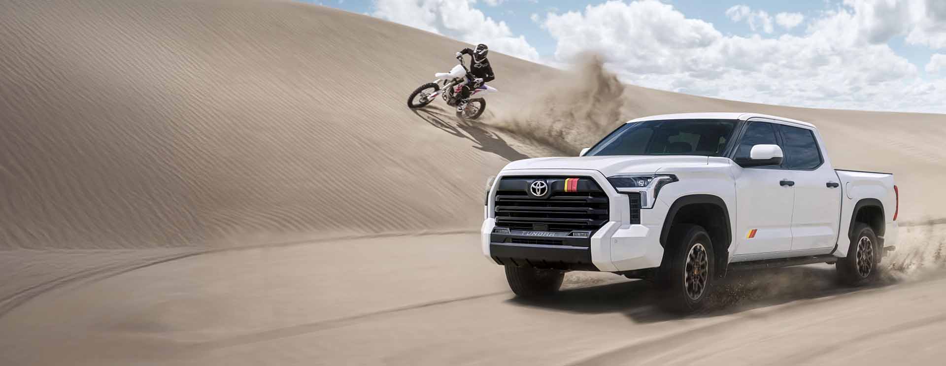 Toyota Tacoma and dirt bike traveling on sand