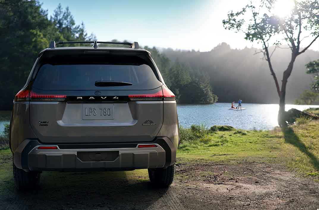 Rav4 parked at coast with people paddleboarding